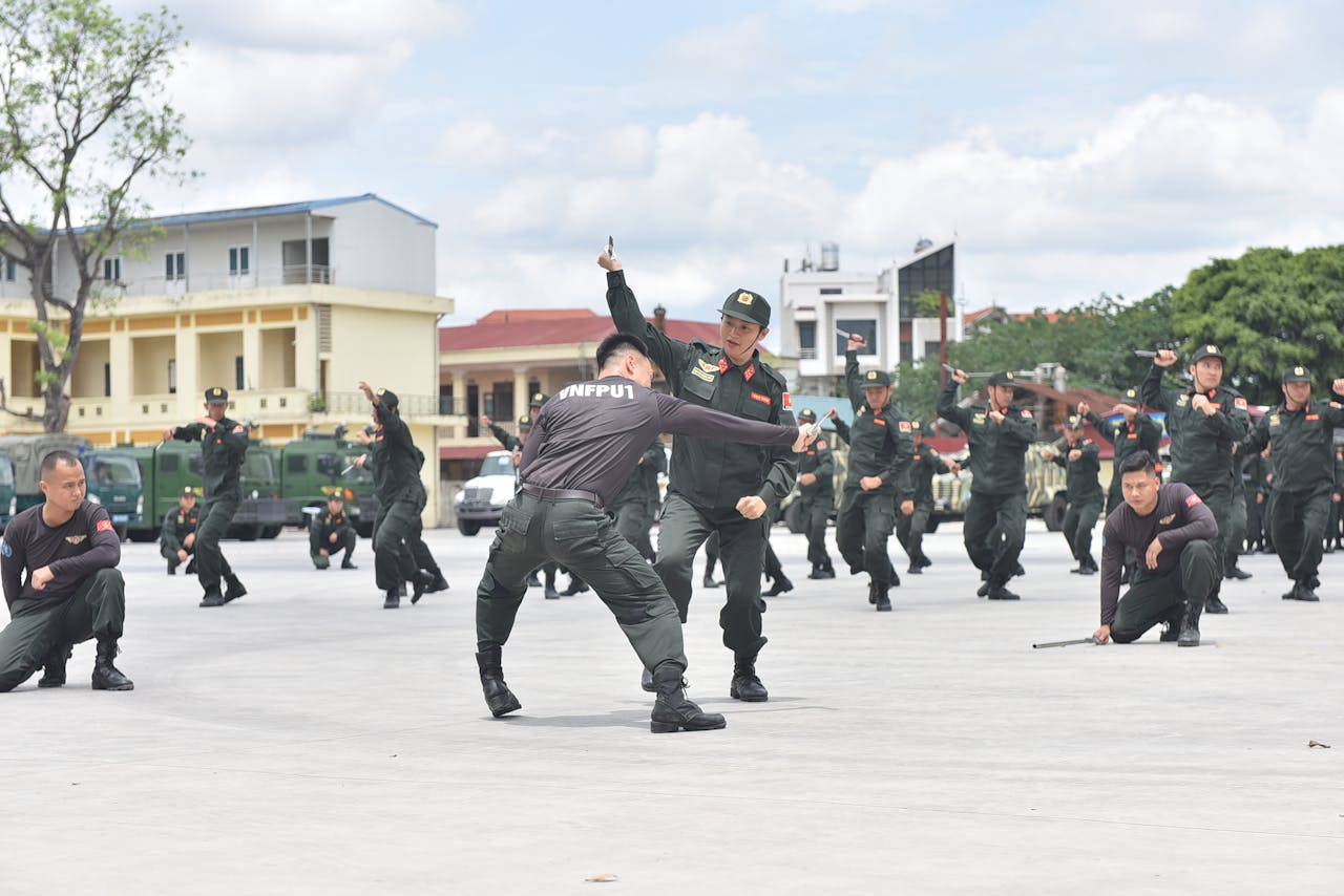 Officers in uniform conduct martial arts drills outdoors during daytime training.
