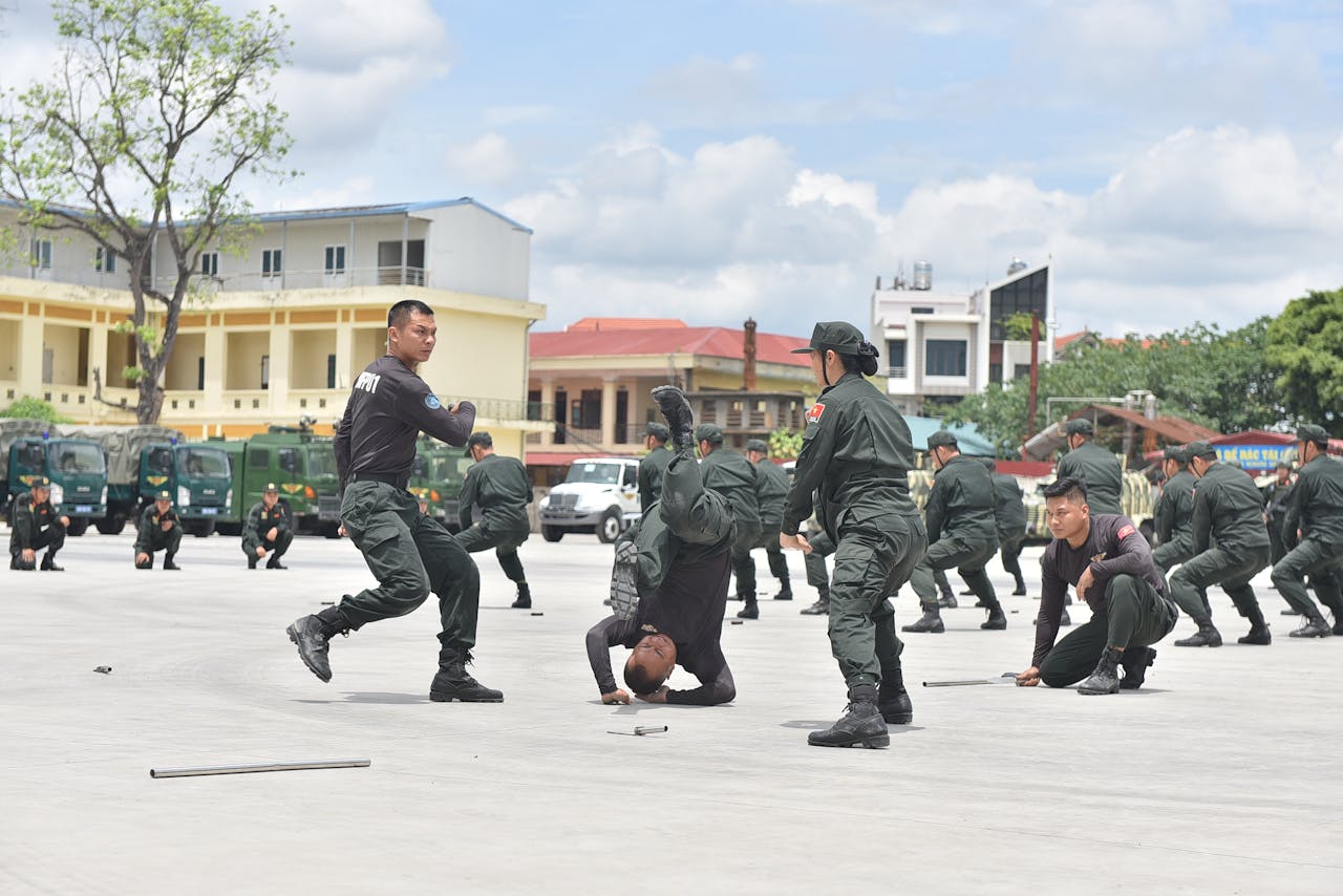 Group of soldiers performing martial arts during a training session outdoors.