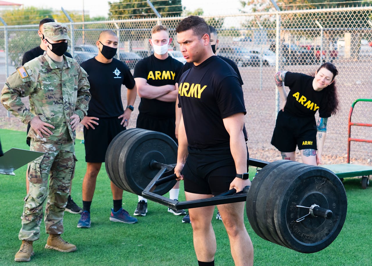 Army personnel participating in an outdoor weightlifting training session, showcasing teamwork and strength.